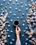 Hand holds a cup of morning coffee and spring flowers with branches blossoming apricots on blue concrete background view