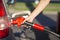 Hand holds gasoline pistol in fuel tank on gas station closeup view.