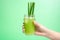 hand holds a glass of aloe vera juice with straws on a bright backdrop