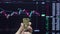 A hand holds a gold bar against the background of a trading price chart.One ounce of gold in your hand.Gold trading on the stock e