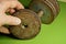 Hand holds a gray rusty metal pancake near a sports dumbbell