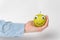 Hand holds green Apple-smiley with Googly eyes. Funny Apple on white background