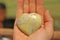 The hand holds a heart made of natural stone yellow jadeite. Heart in hand. A stone in the shape of a heart. Love talisman, zen,