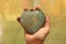 The hand holds the heart from a natural marble stone or green aventurine. Heart in hand. A stone in the shape of a heart. Love