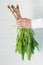 Hand holds horseradish roots with green leaves on a white background