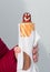 The hand holds hot dog with a smile and ketchup in a close-up on a background a white wall