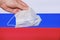 A hand holds a mask against the background of the Russian flag. Coronavirus control in the Russian Federation