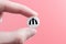 A hand holds a medical pill with a manat currency sign on a pink background. The concept of a rise in the price of medicines in