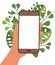 Hand holds mobile phone on background of green leaves. Smartphone with blank screen. Poster, banner, advertisement. Template