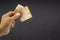 Hand holds one hundred MACEDONIA CURRENCY, Macedonian denar Bank note on black background.