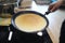 Hand holds pan with pancake, cooking at home