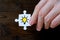 The hand holds a piece of a white puzzle with the image of a light bulb with yellow light on a wooden background. The concept of a