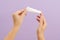 Hand holds plastic cream battle isolated on lilac background. Beauty concept. Packaging tube for cosmetic products