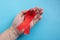 A hand holds a red ribbon on a blue background - the concept of World AIDS Day, Donor Day, Hemophilia Day