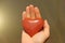 The hand holds a red or terracotta heart made of natural stone. Heart in hand. A stone in the shape of a heart. Love talisman, zen