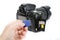 Hand holds SD Memory card with DSLR camera on the background