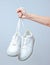 The hand holds by shoelaces hipster white sneakers