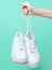 The hand holds by shoelaces hipster white sneakers