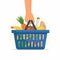 Hand holds shopping basket full of fresh produce. Buy grocery in the supermarket