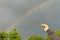 Hand holds a spinner against the rainbow on a gray sky