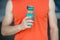 Hand holds sportive bottle of water or sport drink, male body background. Bottle of water in muscular male hand. Sport