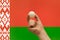 The hand holds a table tennis white ball in front of Belarus flag.