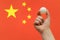 The hand holds a table tennis white ball in front of China flag.