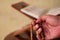 Hand holds tasbih or islamic prayer beads against quran on wooden book stand