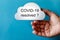 Hand holds a white cloud symbol against a blue background. The text is written on the cloud: COVID-19 resolved