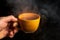 Hand holds a yellow mug with wellness herbal tea close-up. The health drink is recommended by traditional medicine