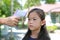 Hand with infrared thermometer measuring forehead of asian little kid girl before entering the playground