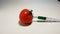 Hand injects a syringe with green liquid gmo in a tomato on a white background