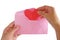 Hand inputting red heart paper origami into pink envelope