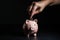 A hand inserting a coin into the piggy bank AI generated