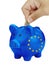 Hand inserting euro coin into Piggy bank with Europe european flag isolated