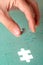 Hand inserting piece of green jigsaw puzzle
