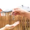 Hand with a key and a wooden key ring-house. Background of fence and cottage. Building, project, moving to a new home, mortgage,