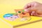 Hand of kid holding wooden jigsaw of the 5 food Groups. Child de