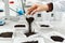 the hand of a lab worker pours black earth on white paper