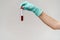 Hand in latex glove holding blood in test tube close up