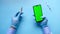 hand in latex gloves holding glass ampoule vaccine and smart phone on blue