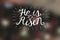 Hand lettering He is risen with a cross.