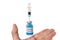 A hand with levitating glass vial labelled coronavirus COVID-19 vaccine and a glass syringe and a needle