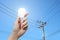 Hand with light bulb, electricity pole background