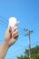 Hand with light bulb, electricity pole background