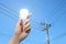 Hand with light bulb, electricity pole background