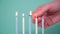 Hand lights five candles isolated on blue or turquoise background. Happy Birthday concept Made of Burning Colorful
