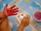 Hand of a little baby being painted with red and green colors - baby handprint / fingerprint painting