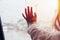 Hand of Little girl looking out of the window with light flare and rain drop on the car door glass, on raining day