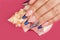 Hand with long artificial blue french manicured nails and a seashell